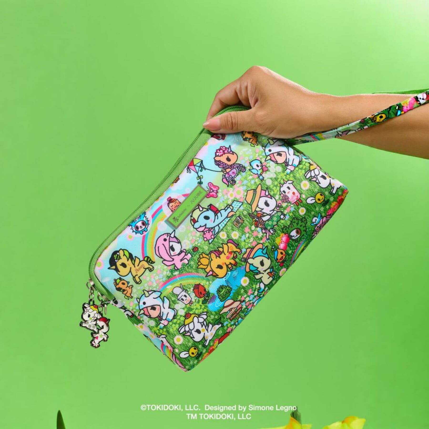 Colorful pouch with cartoon characters held by a hand against a green background