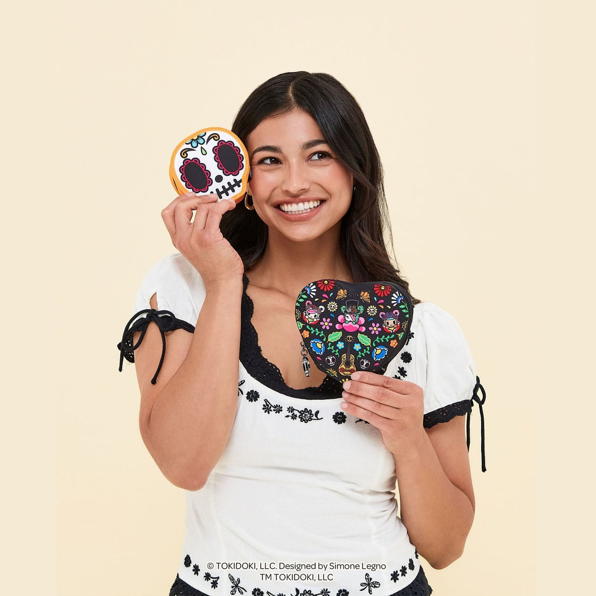 A smiling woman holds tokidoki Heart Mini Bag Clip-On Pouch Accessory – Dia de los Muertos