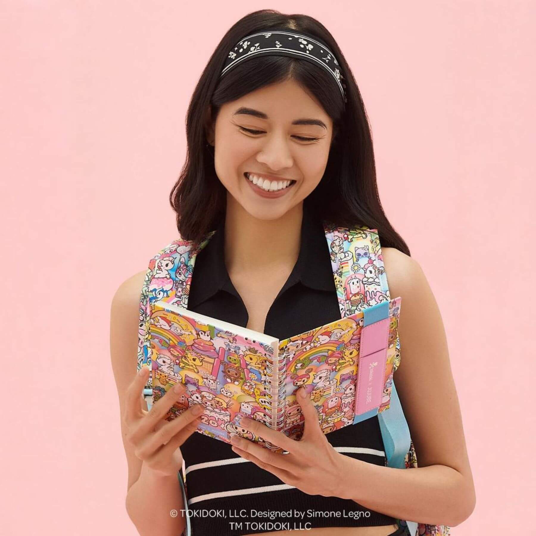 Woman holding tokidoki Spiral Oliver Notebook with a pink background