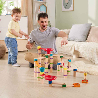 Man and child playing with Hape Tricks n Twists Marble Track in a living room.