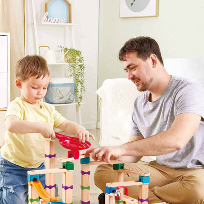 Man and child playing with Hape Tricks n Twists Marble Track in a home setting.