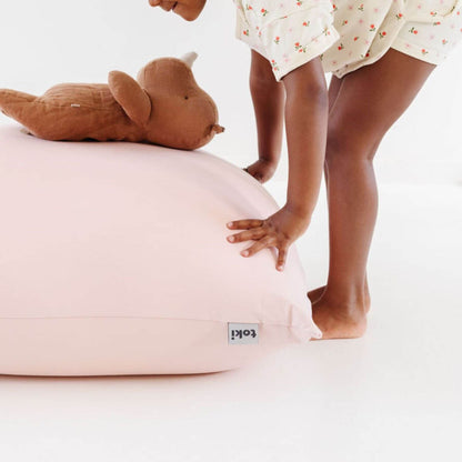 A child pushes Toki Kids Tutu Bean Bag, with a brown plush toy resting on top.