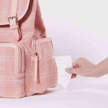 Sunveno Tweed Diaper Backpack Pink with a hand reaching to open a pocket on a light pink background