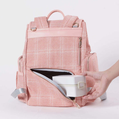 Sunveno Tweed Diaper Backpack Pink with a hand opening a compartment on a light background