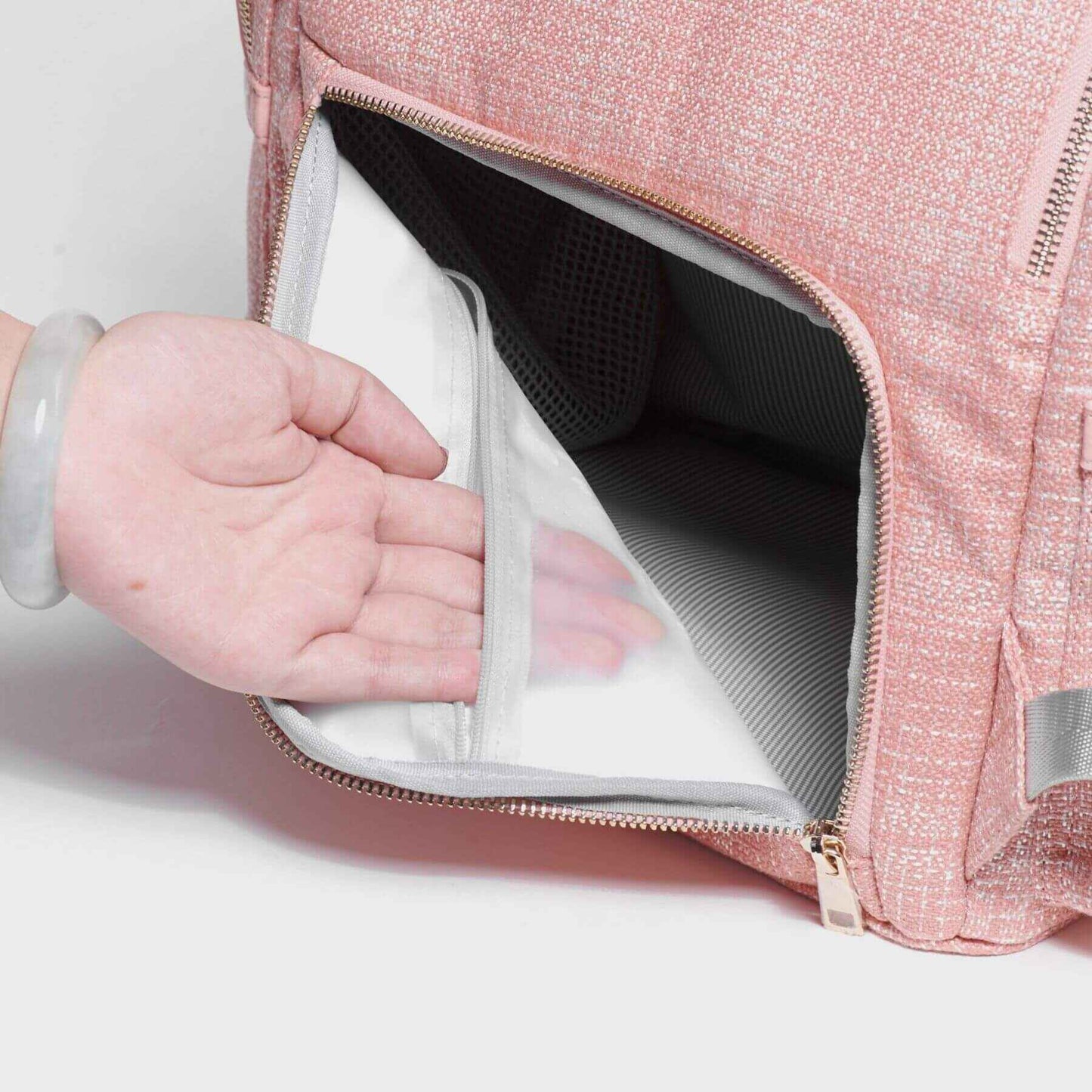 Sunveno Tweed Diaper Backpack Pink with a hand reaching inside, showing a clear compartment.