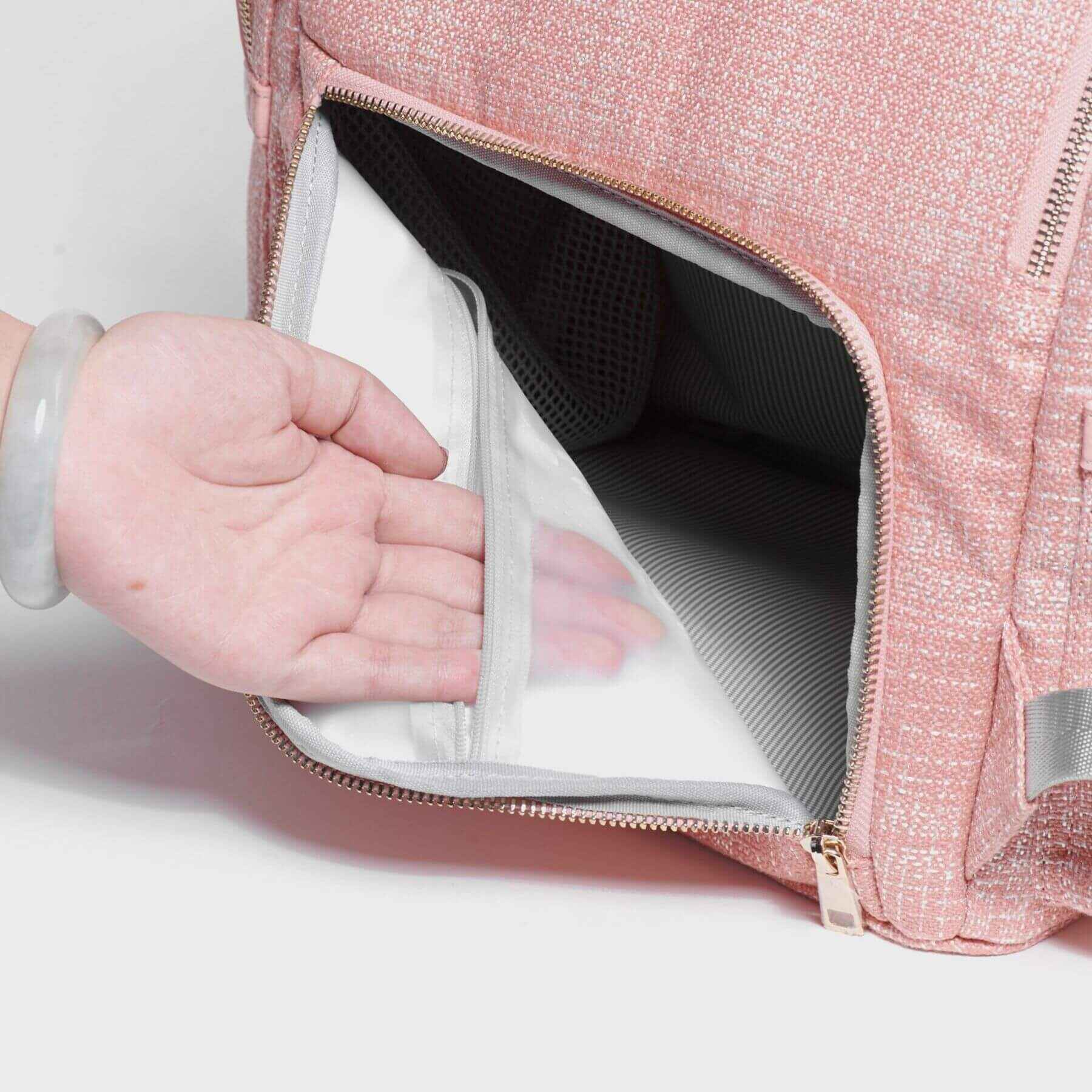 Sunveno Tweed Diaper Backpack Pink with a hand reaching inside, showing a clear compartment.