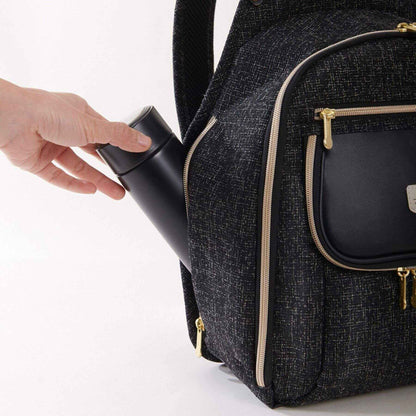 Sunveno Tweed Luxe Diaper Bag Backpack - Black with a hand placing a black container into one of its compartments on a white background