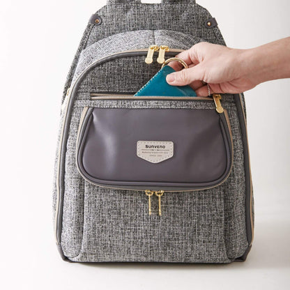 Sunveno Tweed Luxe Diaper Bag Backpack - Gray with a hand opening a small gray pouch, on a white background