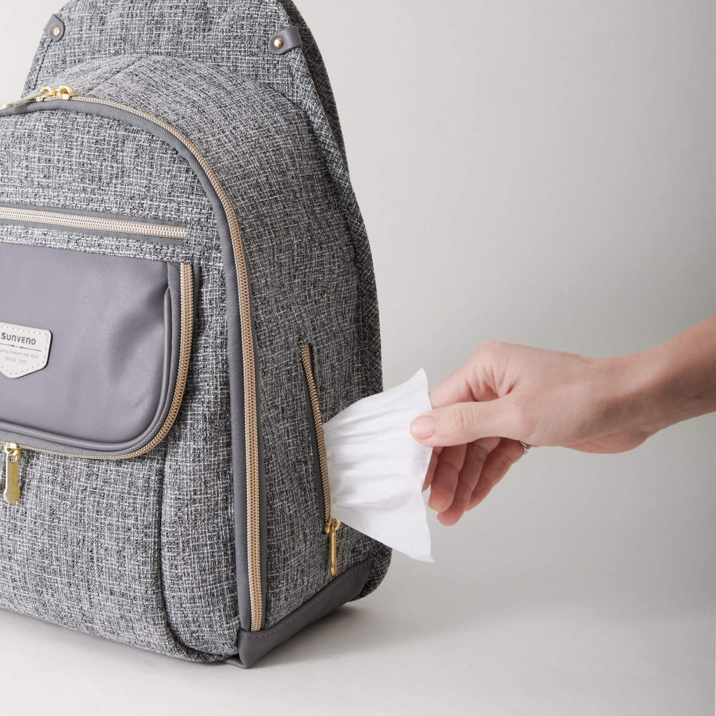 Person taking a wipe from Sunveno Tweed Luxe Diaper Bag Backpack - Gray on a light gray background