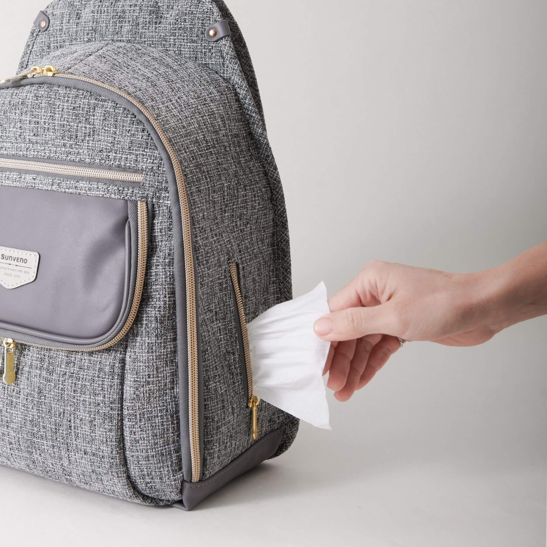 Person taking a wipe from Sunveno Tweed Luxe Diaper Bag Backpack - Gray on a light gray background