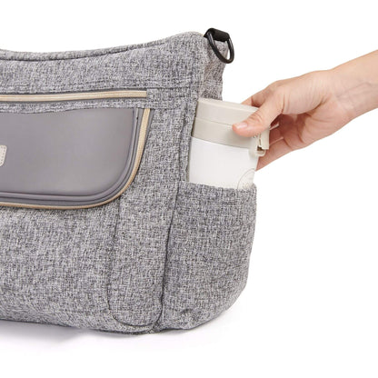 Tweed Luxe Stroller Organizer Grey with a hand placing a white container into a pocket on a white background