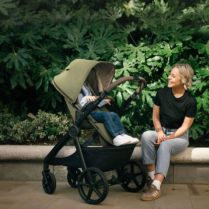 Woman sitting next to Mompush Ultimate 3 - Titanium with a child in a garden setting