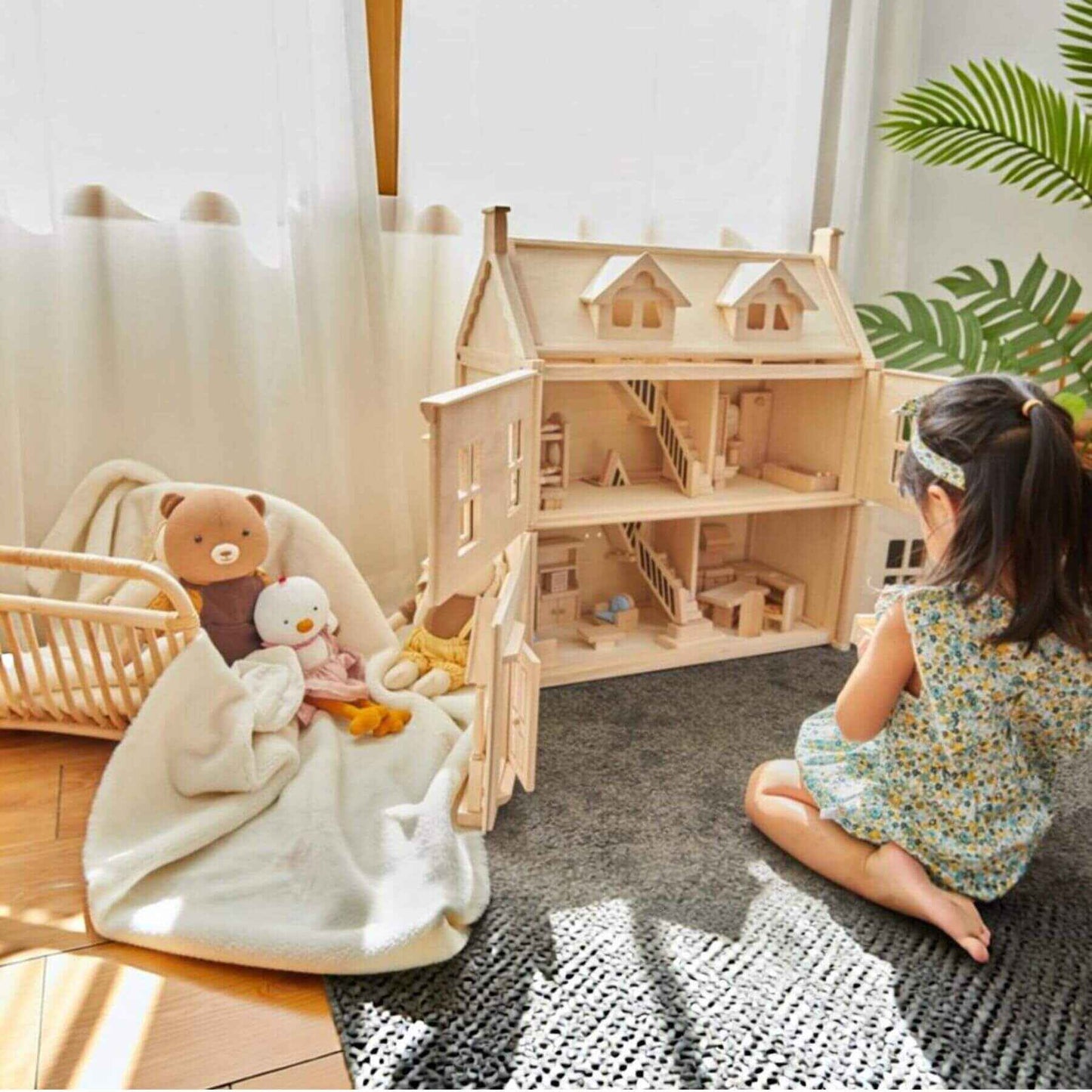 Child playing with PlanToys Victorian Dollhouse and stuffed animals in a cozy room.