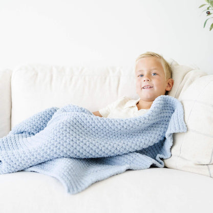 Child lying on a couch with Saranoni Waffle Knit Toddler Blanket - Blue Jay