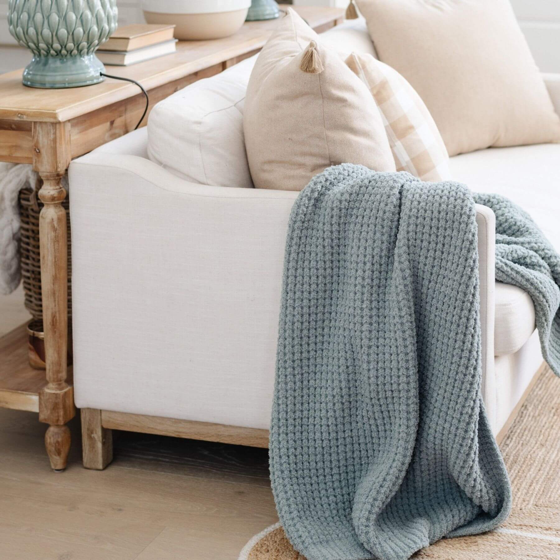 Cozy living room with a white sofa, Saranoni Waffle Knit Toddler Blanket - Elm, and wooden side table.
