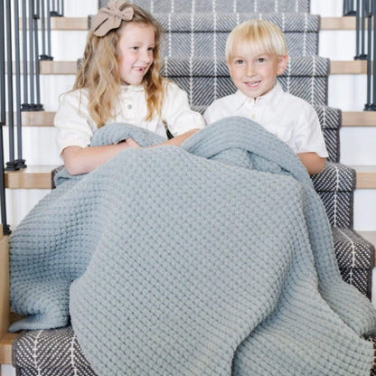 Two children sitting on a staircase with Saranoni Waffle Knit Toddler Blanket - Elm