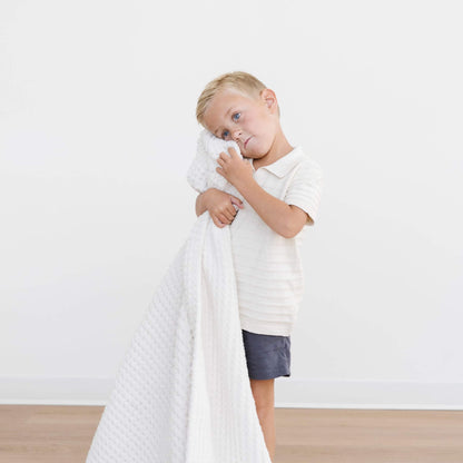 Child holding Saranoni Waffle Knit Toddler Blanket - Swan against a plain background