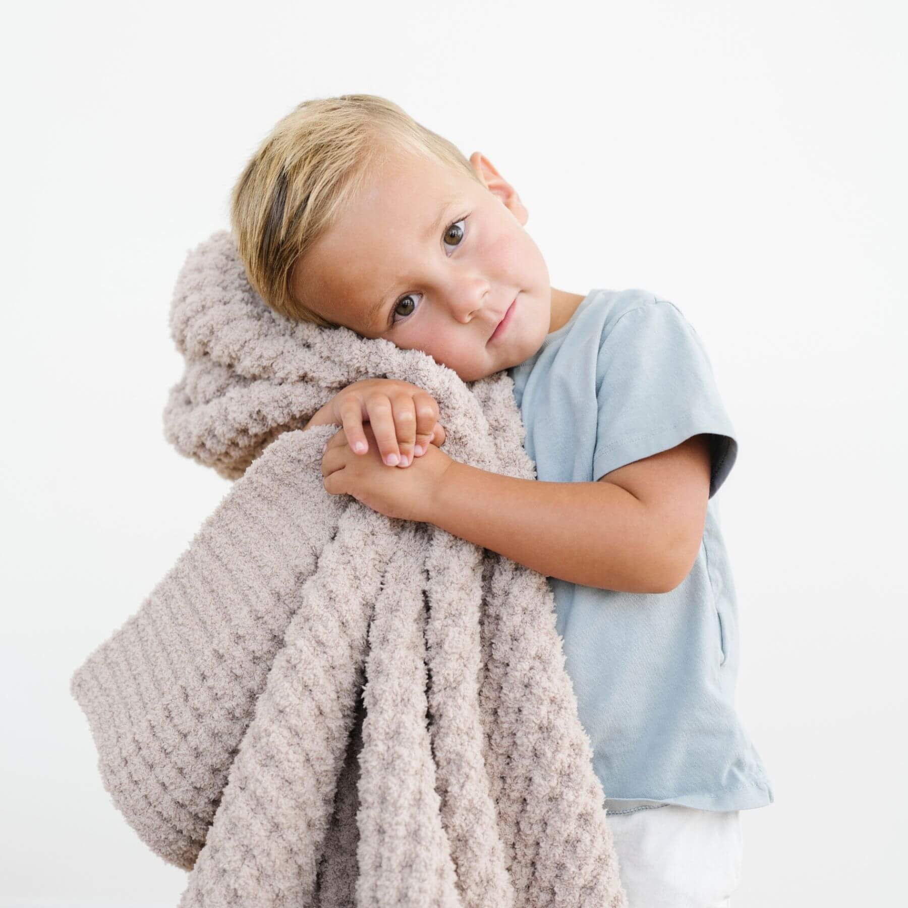 Child holding Saranoni Waffle Knit Toddler Blanket - Wheat against a white background
