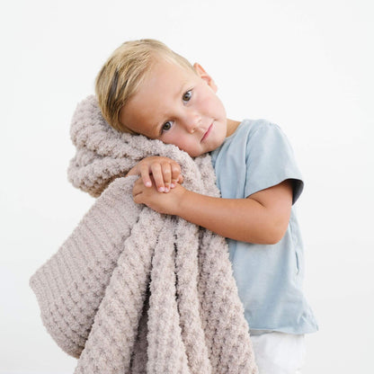 Child holding Saranoni Waffle Knit Toddler Blanket - Wheat against a white background