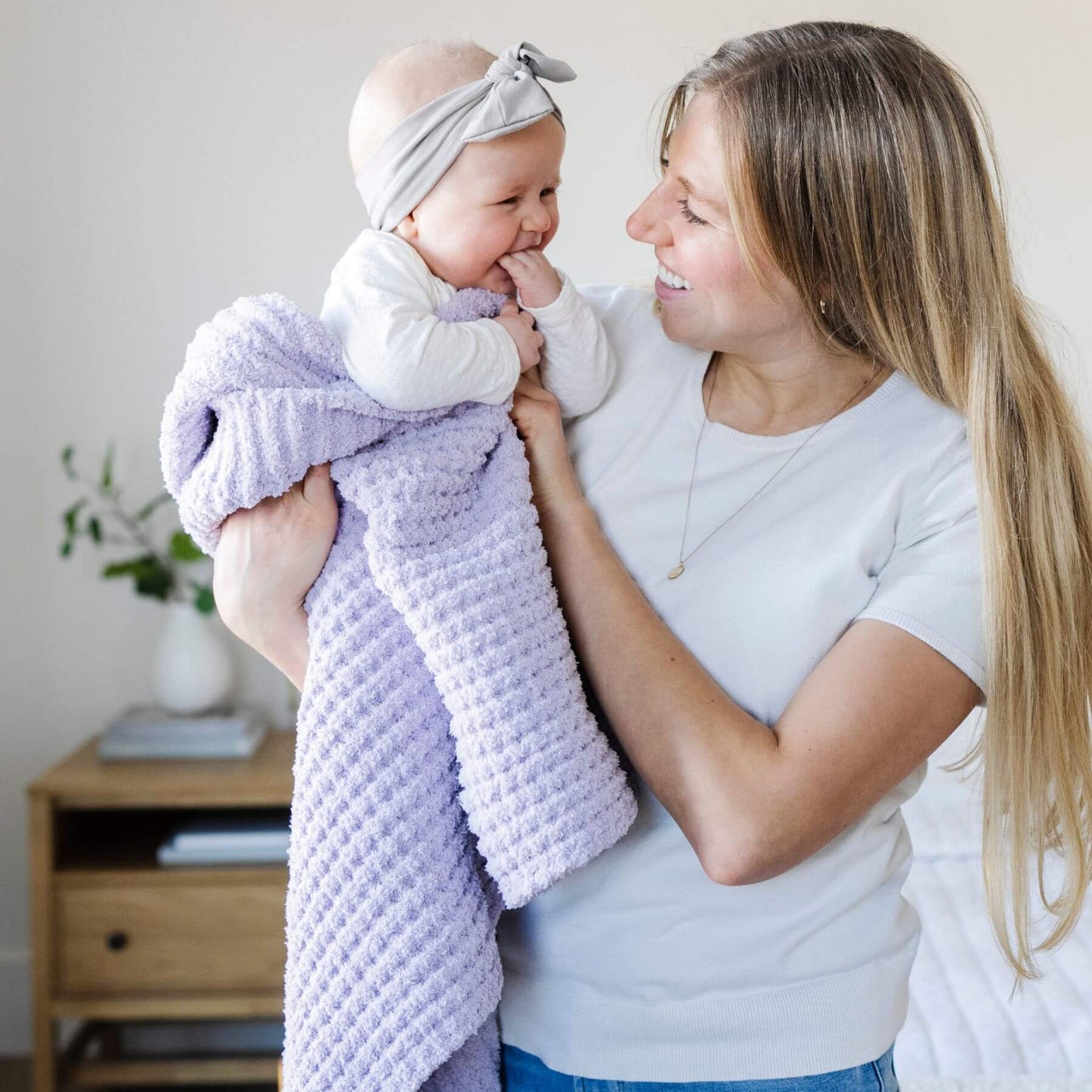 Woman holding a baby wrapped in Saranoni Waffle Knit Toddler Blanket - Wisteria indoors