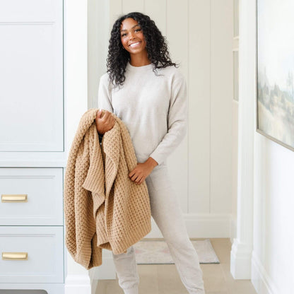 Woman holding Saranoni Waffle Knit XL Throw Blanket - Allspice in a neutral-colored room