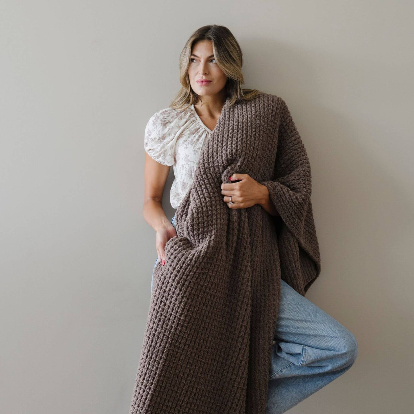 Woman wearing Saranoni Waffle Knit XL Throw Blanket - Chestnut against a plain background