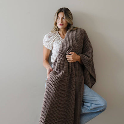 Woman wearing Saranoni Waffle Knit XL Throw Blanket - Chestnut against a plain background