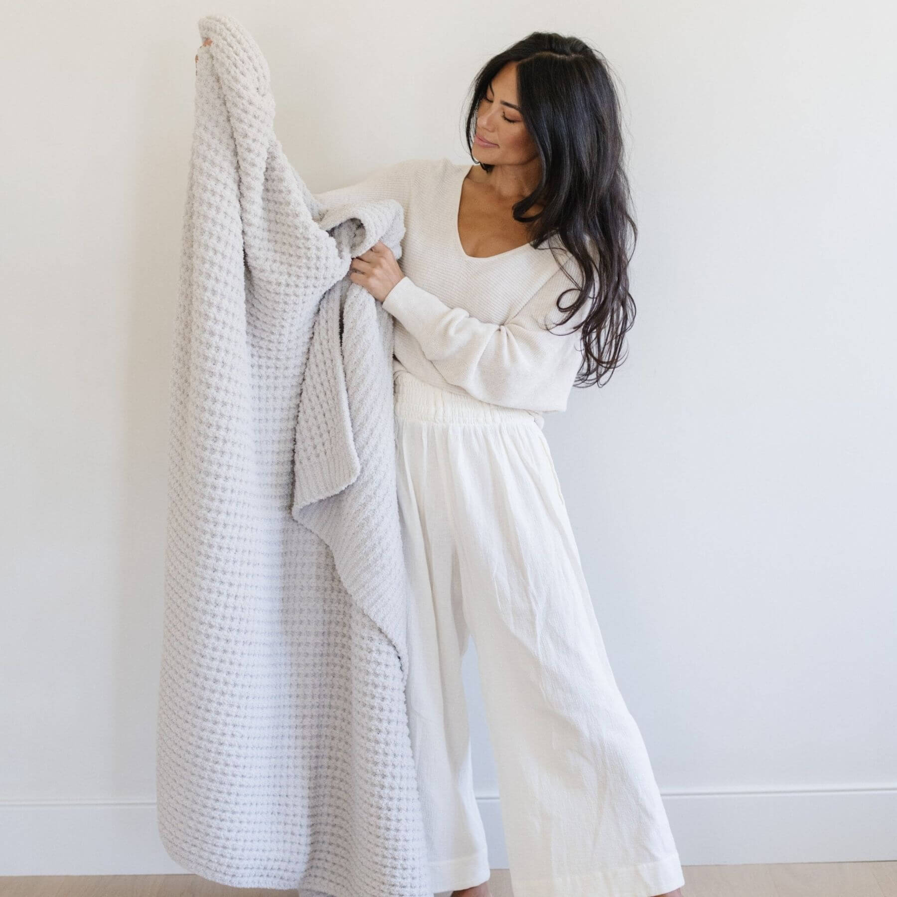 Woman holding Saranoni Waffle Knit XL Throw Blanket - Moonbeam against a plain background