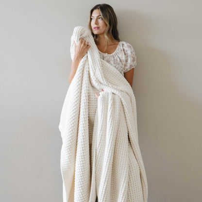Woman holding Saranoni Waffle Knit XL Throw Blanket - Swan against a plain background