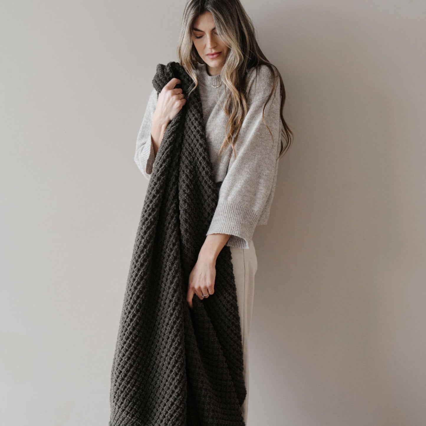 Woman holding Saranoni Waffle Knit XL Throw Blanket - Thyme against a plain background