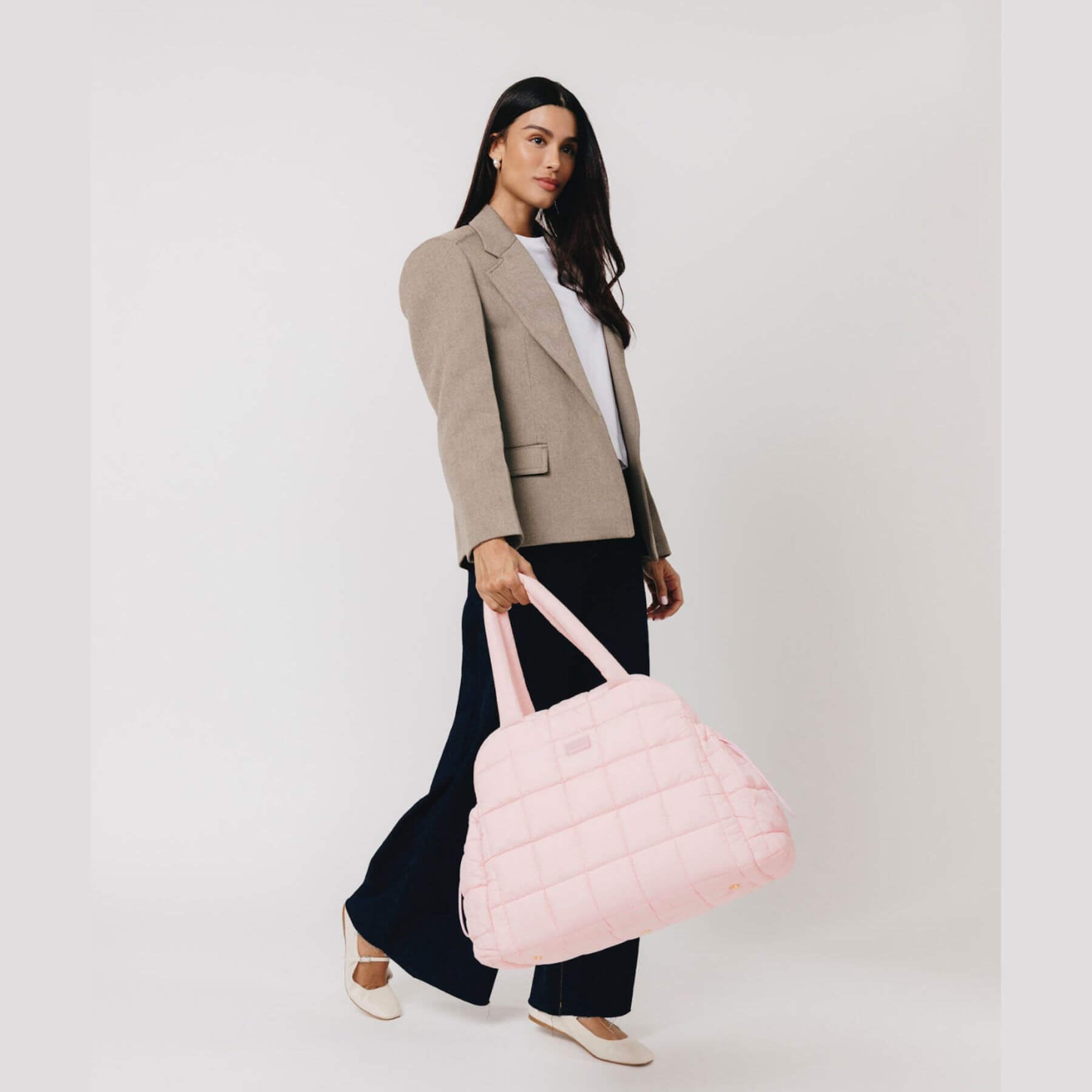 Woman holding augustnoa the weekender duffle bag pink against a white background