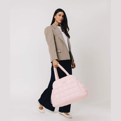 Woman holding augustnoa the weekender duffle bag pink against a white background