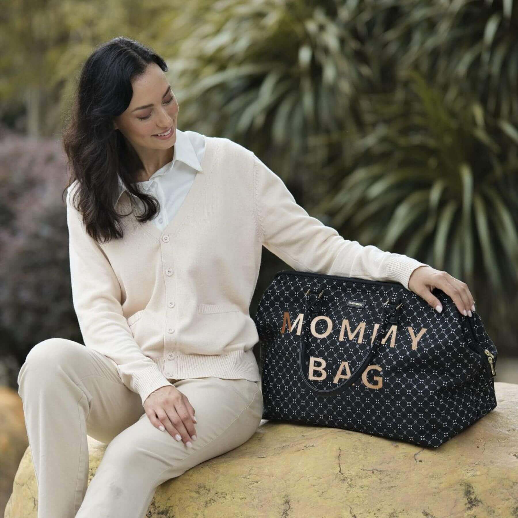 Woman sitting with Sunveno Weekender Mommy Bag Travel Duffle - Black on a rock outdoors