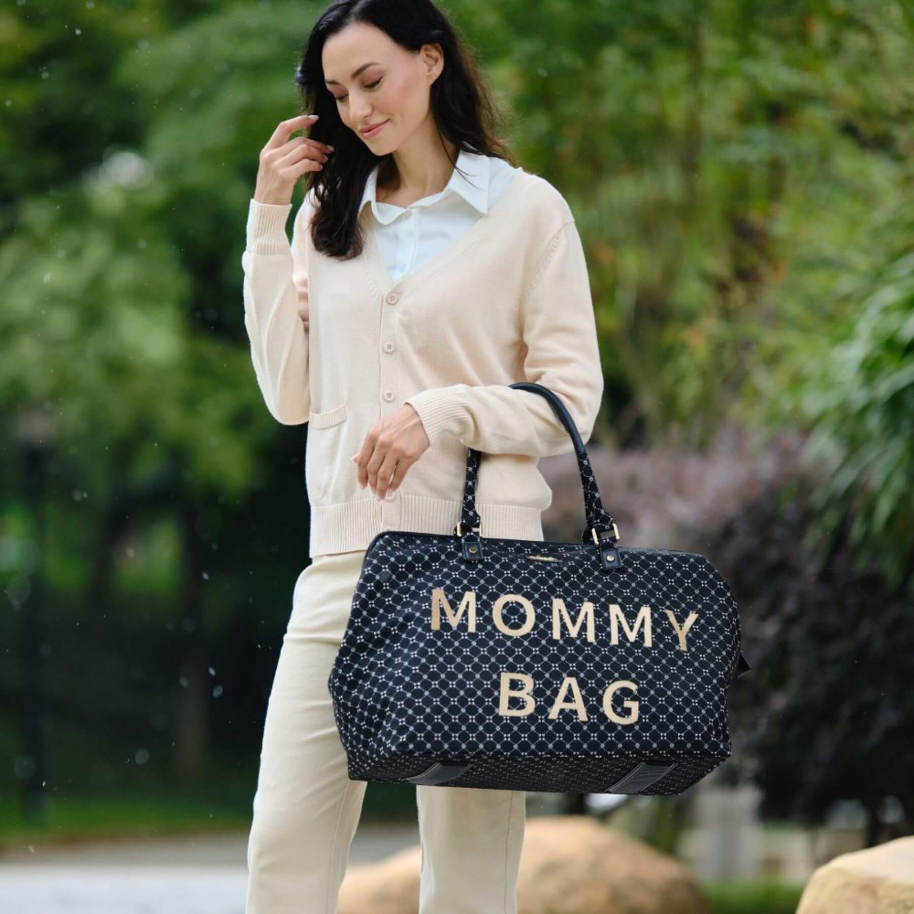 Woman holding Sunveno Weekender Mommy Bag Travel Duffle - Black in a park-like setting