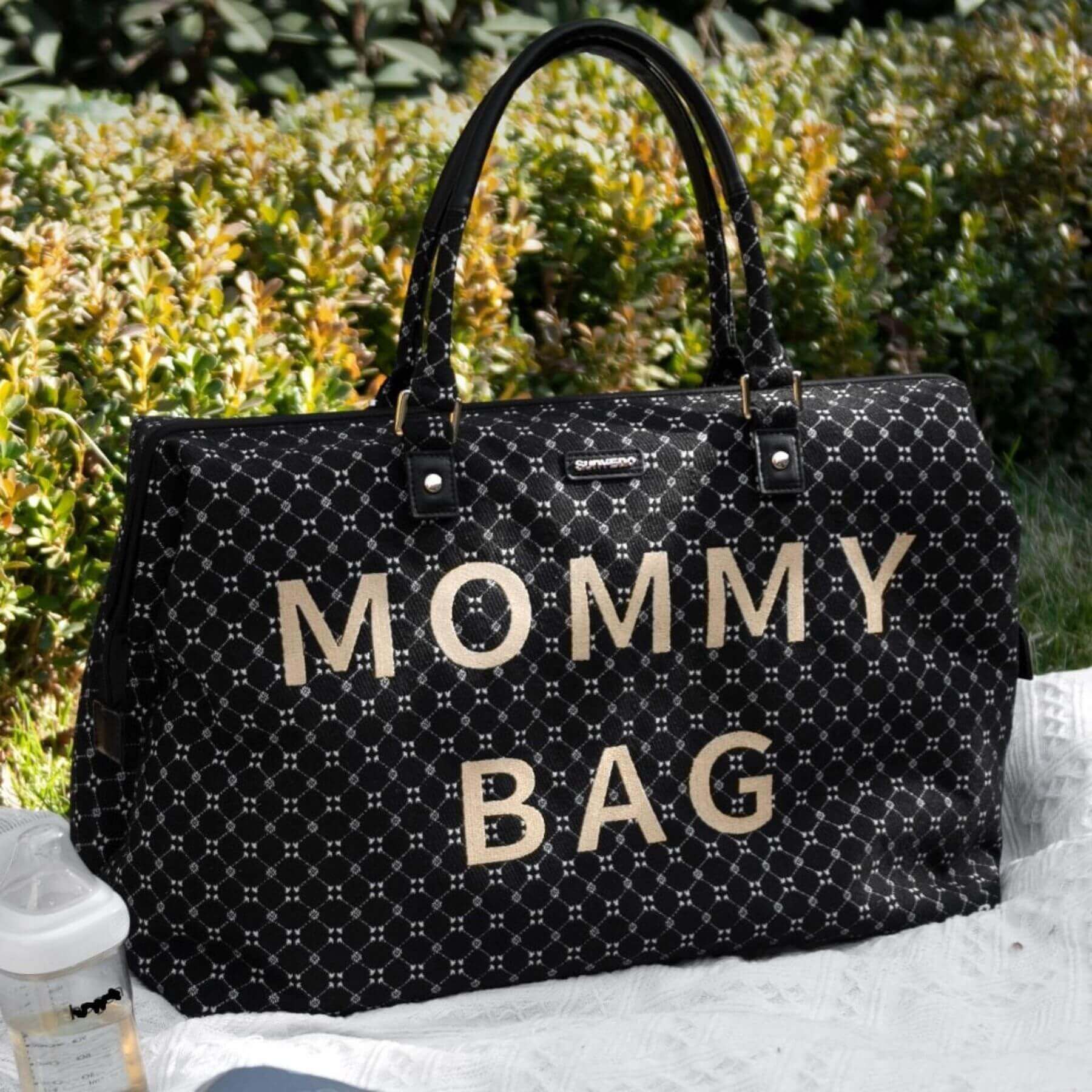 Sunveno Weekender Mommy Bag Travel Duffle - Black on a white surface with greenery in the background