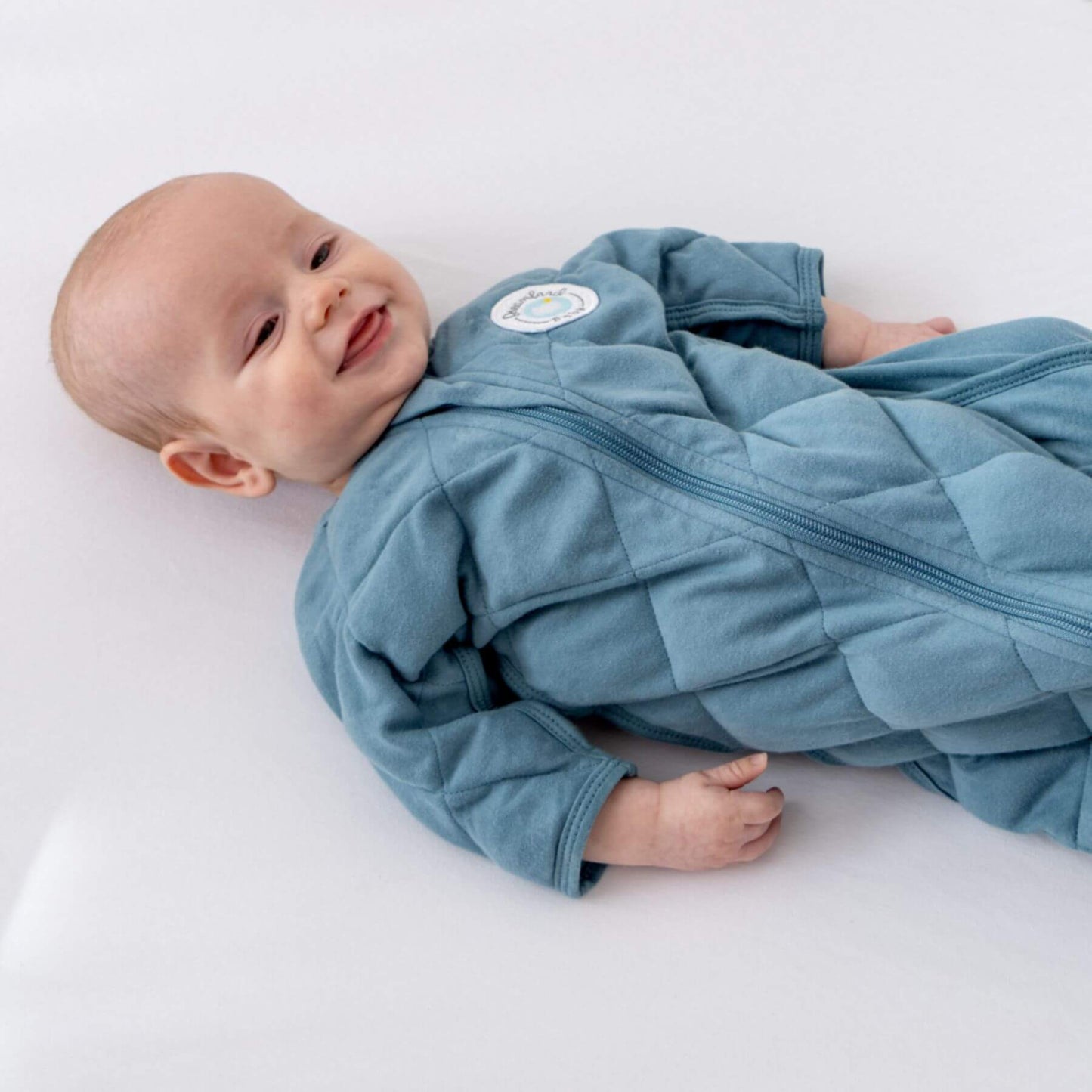 Baby wearing Dream Weighted Transition Swaddle - Ocean Blue on a white background