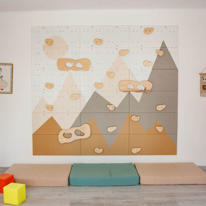 Wood and Hearts Indoor Climbing Wall on a white wall, with colorful cushions and blocks on the floor.