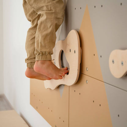 Child's feet stepping onto a wooden step stool attached to a wall.