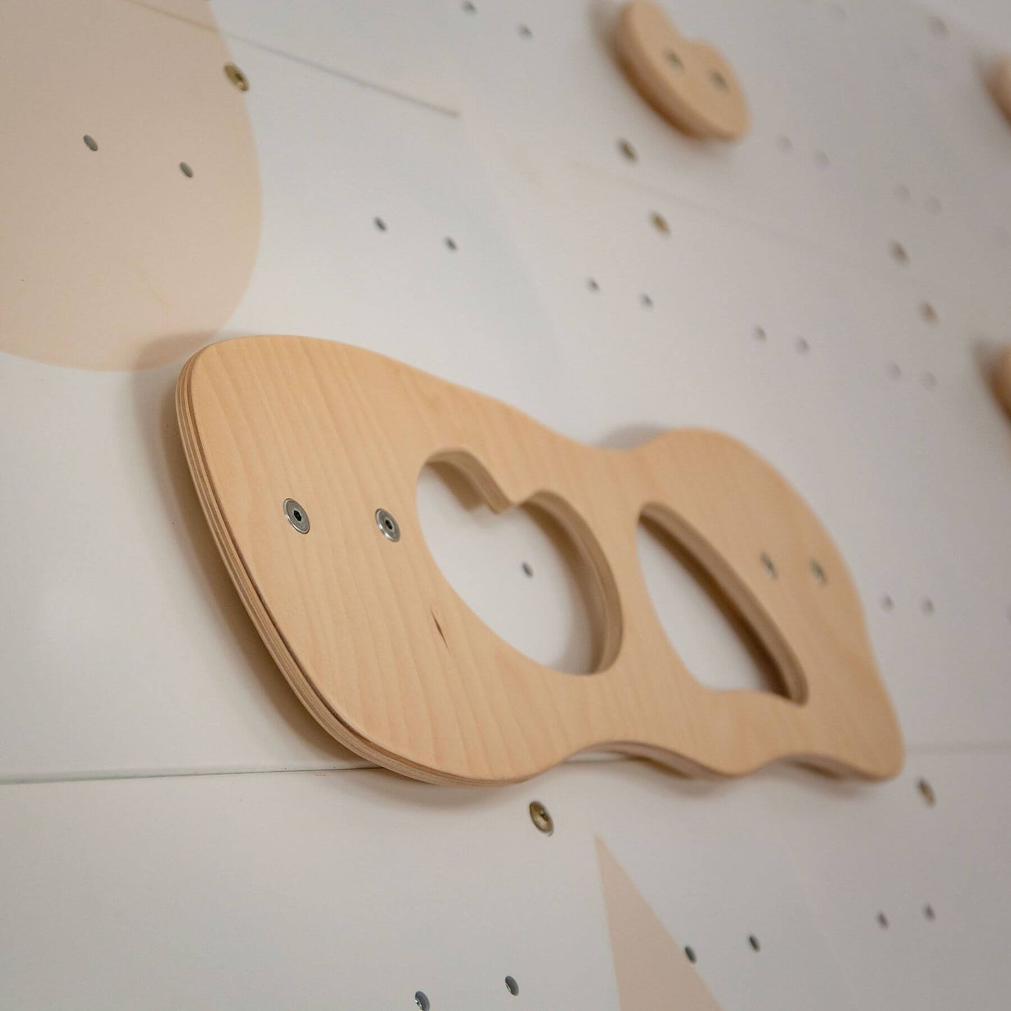 Wooden climbing toy on a white wall with black dots