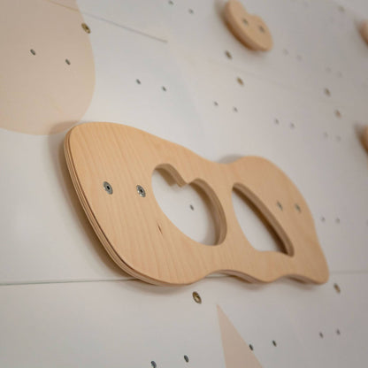 Wooden climbing toy on a white wall with black dots