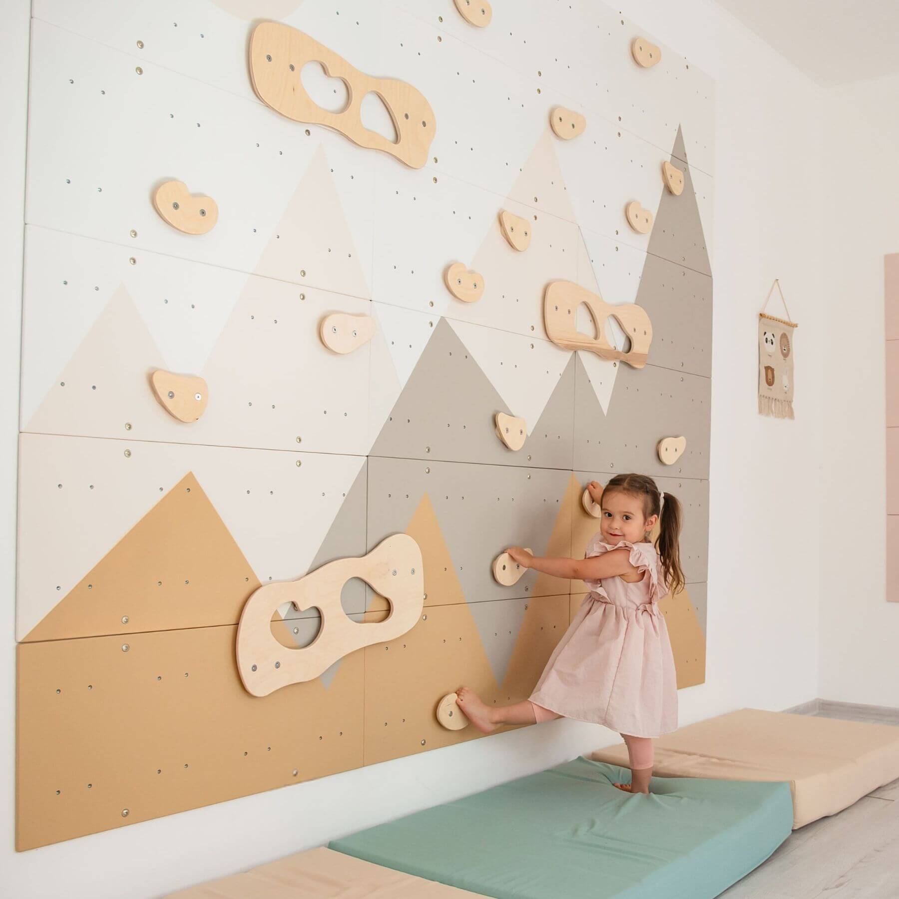 Child playing on Wood and Hearts Indoor Climbing Wall holds in a room.