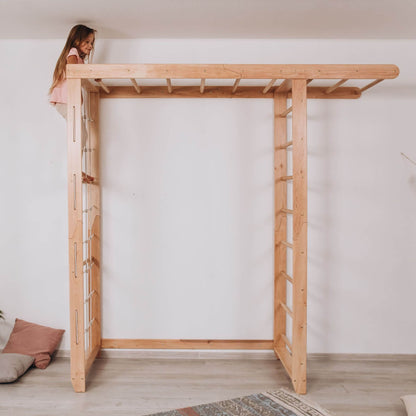 Wood and Hearts Indoor Monkey Bars - Natural with a child standing on top in a minimalistic room.