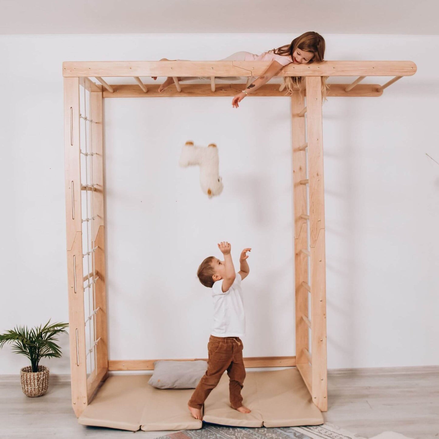 Two children playing on Wood and Hearts Indoor Monkey Bars - Natural in a minimalistic room.