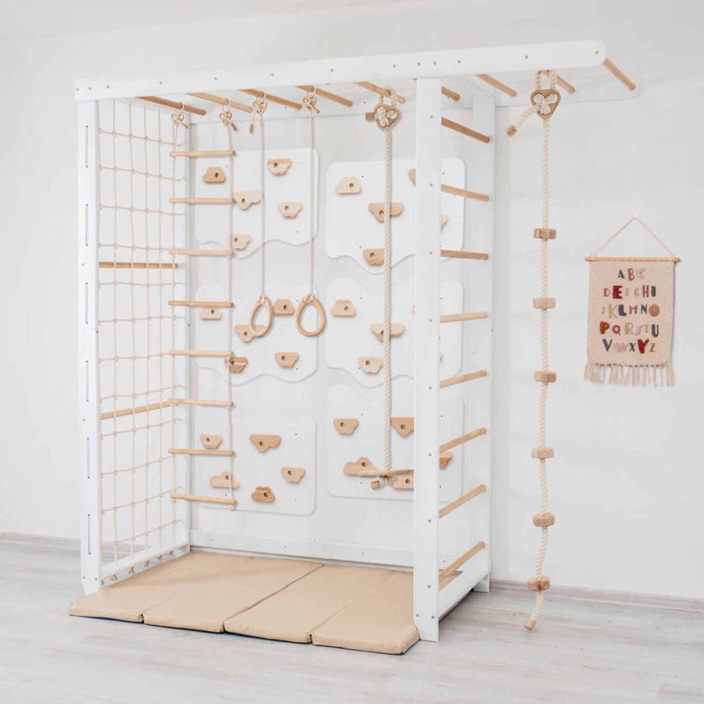 Wood and Hearts Indoor Monkey Bars - White and a soft landing mat on a light wooden floor.