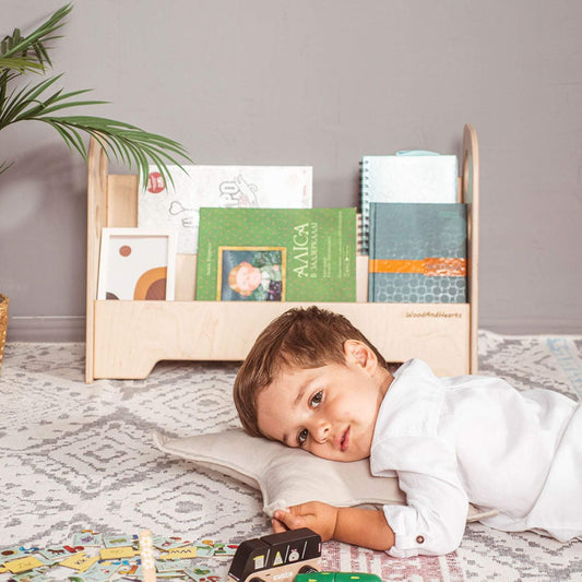 Boy Lying in front of Wood and Hearts Kids Bookshelf in Natural Wood