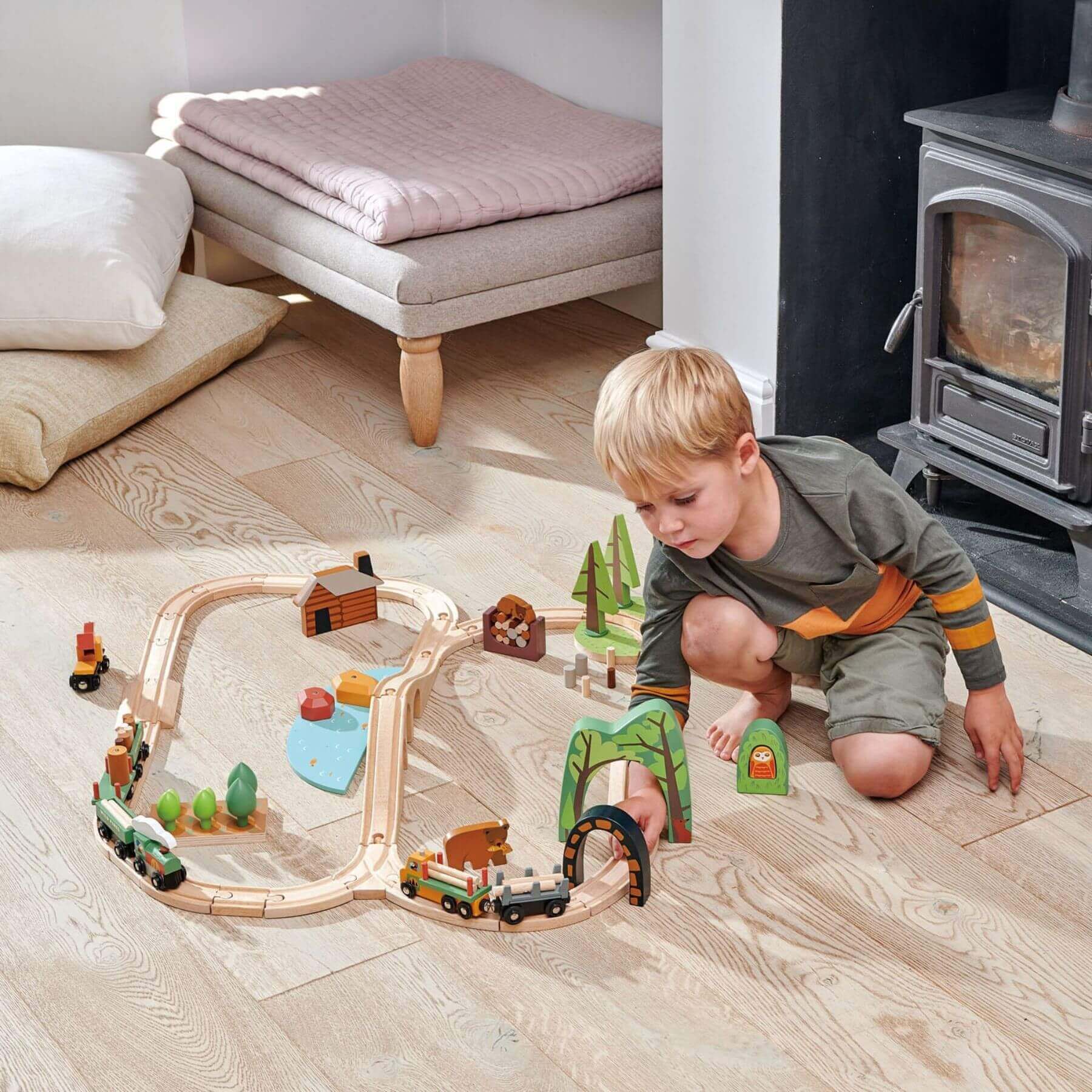 Child playing with Tender Leaf Wild Pines Train Set on a wooden floor.