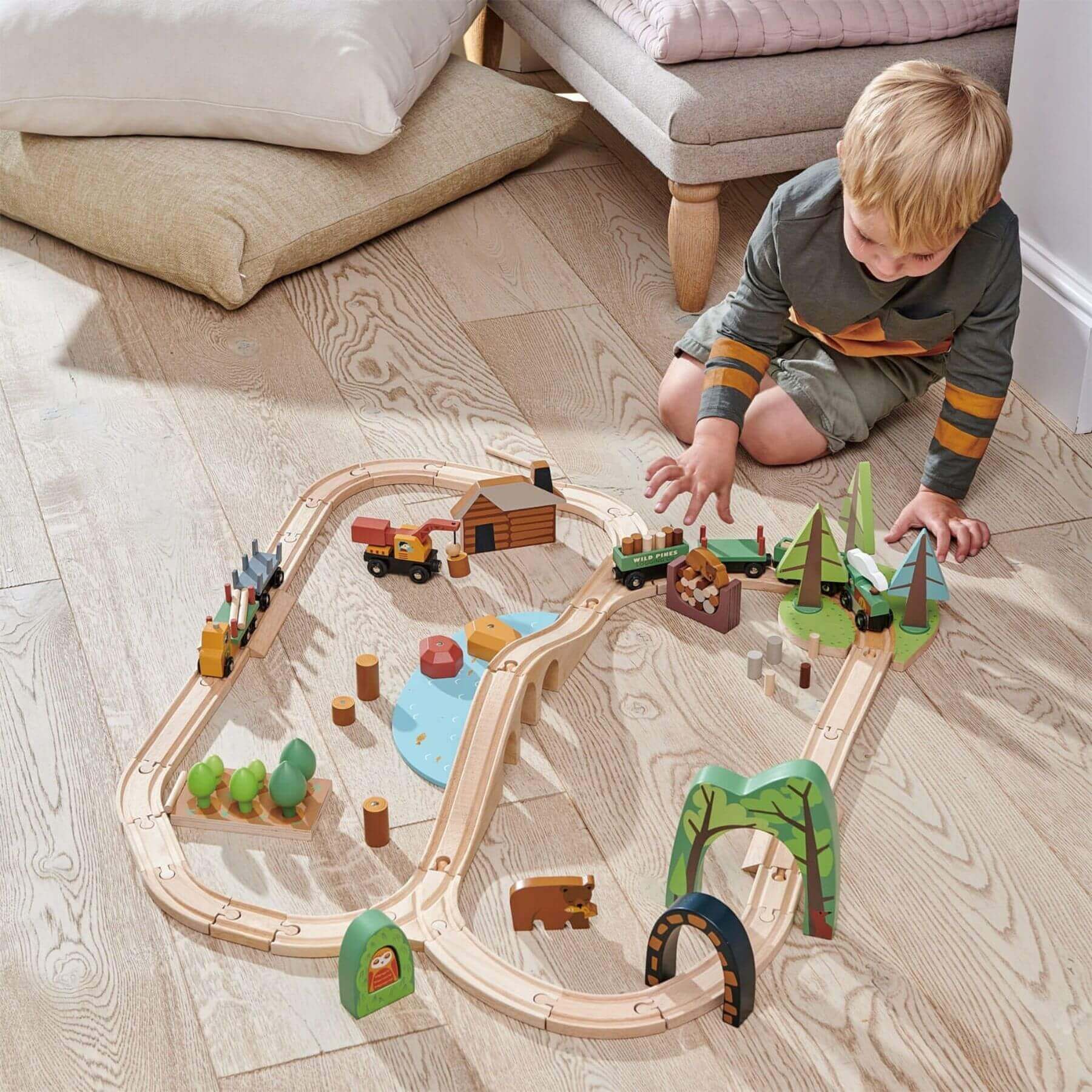 Child playing with Tender Leaf Wild Pines Train Set on a wooden floor.
