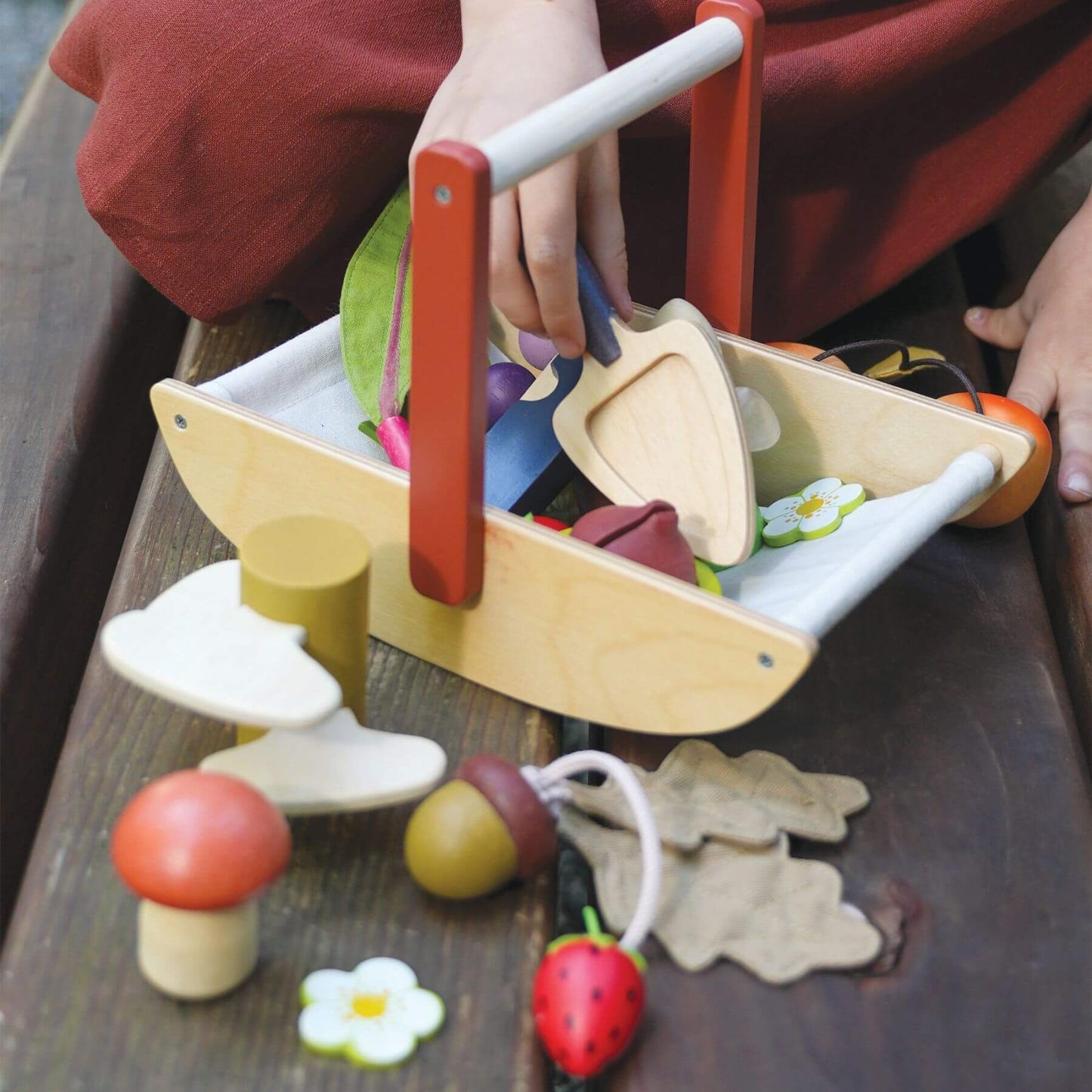 Child playing with Tender Leaf Wild Wood Foraging Trug on a wooden surface.