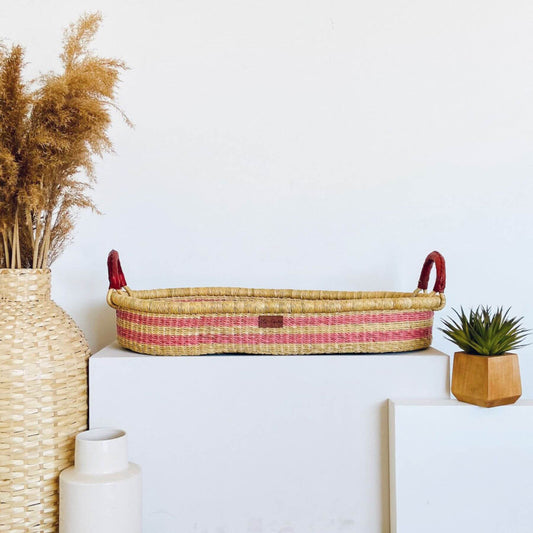 Plum+Sparrow Wildflower Changing Basket on a white surface, surrounded by decorative items.