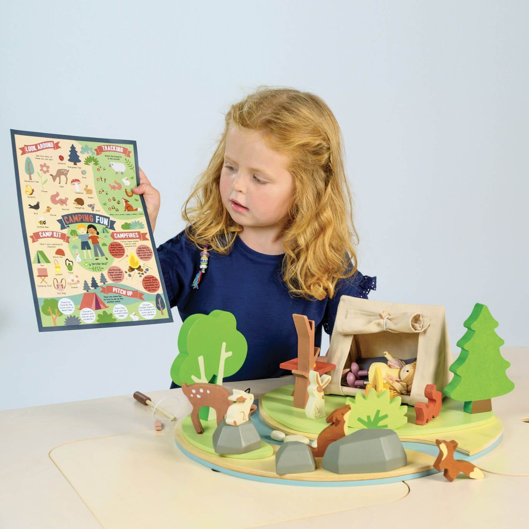 Child playing with Tender Leaf Wildlife Camping Playset, holding a map.